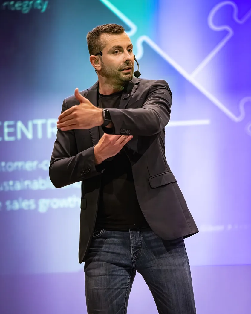 Oliver Albrecht on stage with a headset microphone during a talk